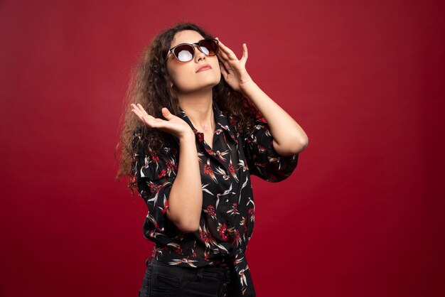 Mujer rizada en gafas de sol de pie.