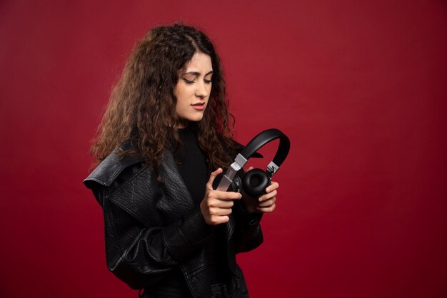 Mujer rizada mirando auriculares.