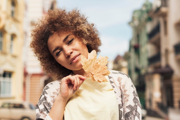 Mujer rizada posando con una hoja