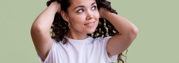 Mujer rizada sosteniendo su cabello en estudio