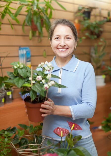 Mujer rodeada de diferentes flores en la tienda de flores