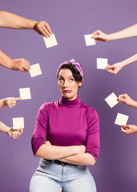 Mujer rodeada de manos y notas adhesivas siendo indiferente