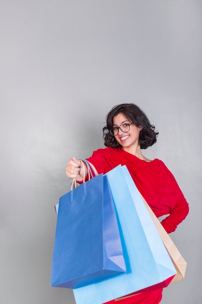 Foto gratuita mujer en rojo dando bolsas de compras