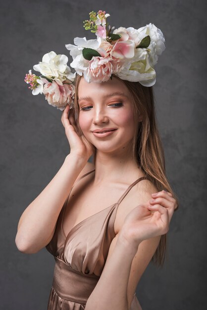 Mujer romántica alegre joven en vestido con hermosa guirnalda de flores