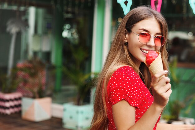Mujer romántica comiendo helado y sonriendo a la cámara, disfrutando de las vacaciones de verano, viaje a islas tropicales