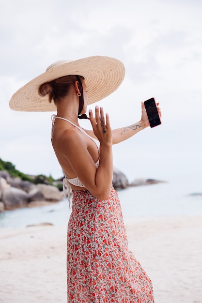 Mujer romántica en la playa en falda de punto superior y sombrero de paja