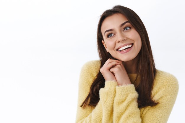 Mujer romántica soñadora en suéter amarillo soñando con algo hermoso, cita perfecta en un buen día de primavera, mirando a un lado pensativo y sonriendo despreocupado, concepto de felicidad