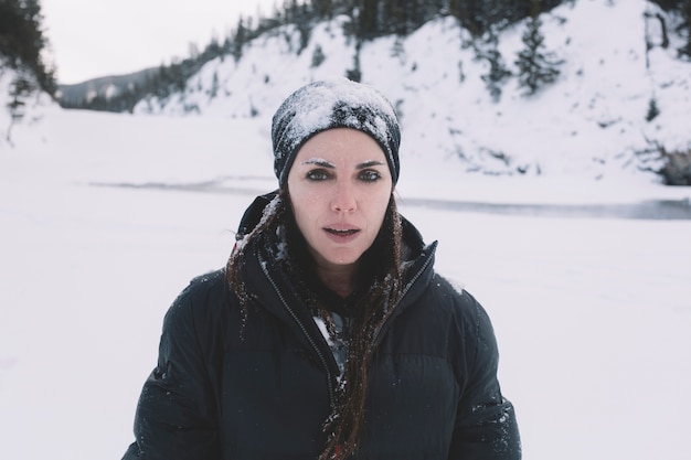 Mujer en ropa de abrigo en el fondo cubierto de nieve