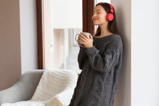 Foto gratuita mujer en ropa acogedora con taza y auriculares