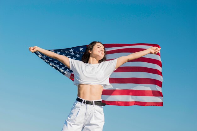 Mujer en ropa blanca con gran bandera de Estados Unidos