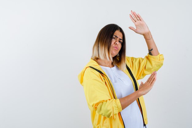 Mujer en ropa casual bailando, haciendo olas, disfrutando de la música y mirando divertida, vista frontal.