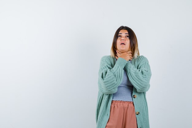 Mujer en ropa casual que sufre de dolor de garganta y parece enferma, vista frontal.