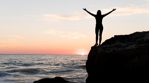 Mujer en ropa deportiva disfrutando de la puesta de sol