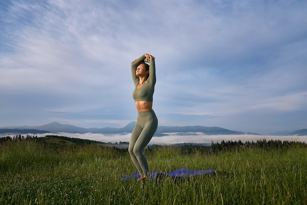 Foto gratuita mujer en ropa deportiva haciendo ejercicios de yoga en la naturaleza