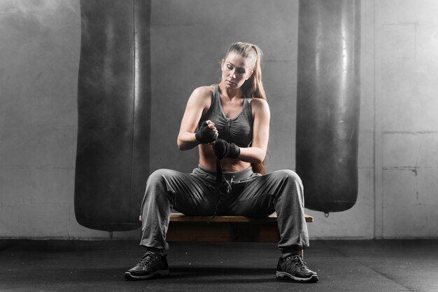 Mujer en ropa deportiva sentado en el banco y preparándose para el entrenamiento