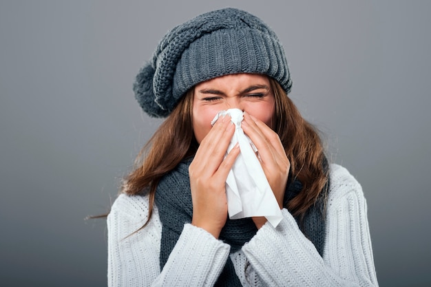 Mujer en ropa de invierno estornudos