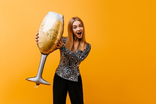 mujer en ropa de moda jugando en la fiesta de cumpleaños. retrato de mujer hermosa sonriente con copa de vino gigante.