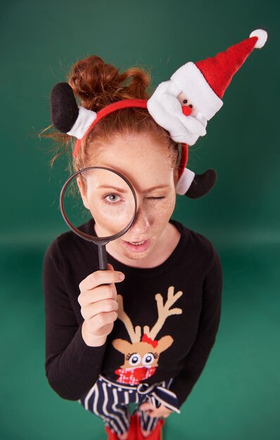 Mujer en ropa de navidad mirando con lupa