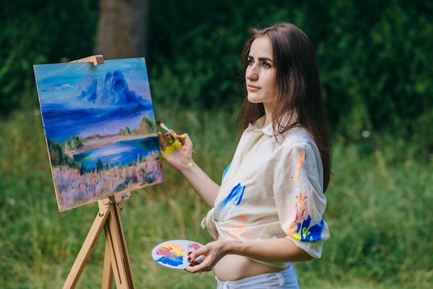 Foto gratuita mujer con la ropa sucia de pintura pintando un cuadro