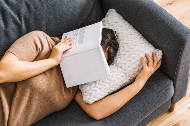 Foto gratuita mujer sin rostro con el libro durmiendo en el sofá