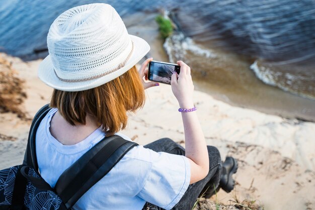 Mujer sin rostro tomando foto del mar