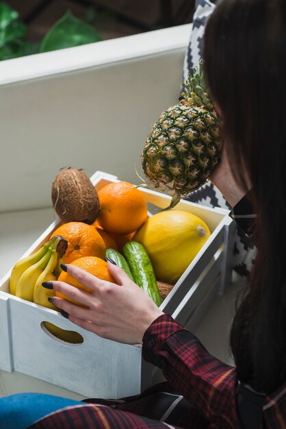 Mujer sin rostro tomando frutas de la caja