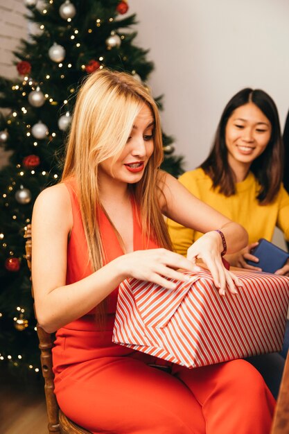 Mujer rubia abriendo regalo en cena de navidad