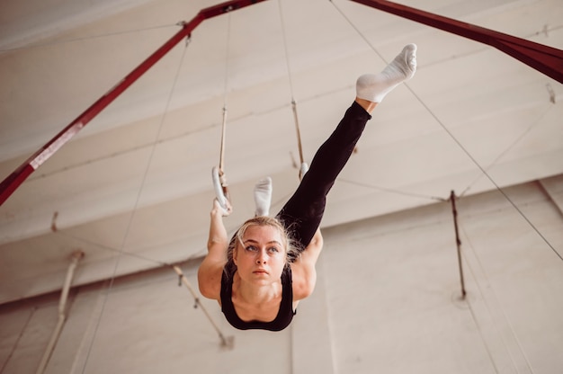 Foto gratuita mujer rubia de ángulo bajo formación en anillos de gimnasia