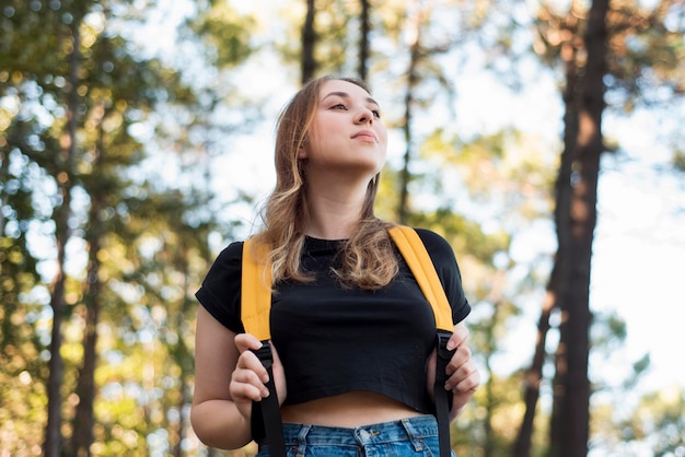 Foto gratuita mujer rubia de ángulo bajo con mochila en bosque