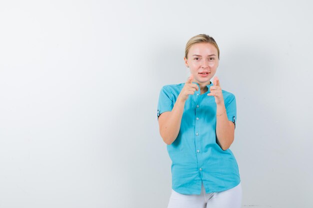 Mujer rubia apuntando a la cámara en blusa azul y mirando feliz aislado