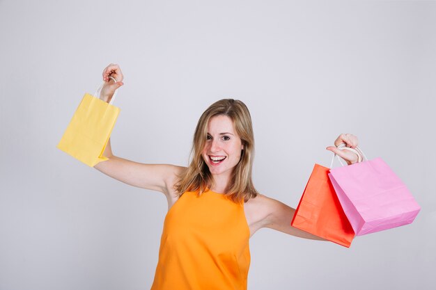 Mujer rubia bailando con bolsas de compra