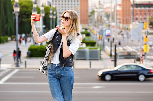 Mujer rubia bastante turista haciendo selfie en la calle
