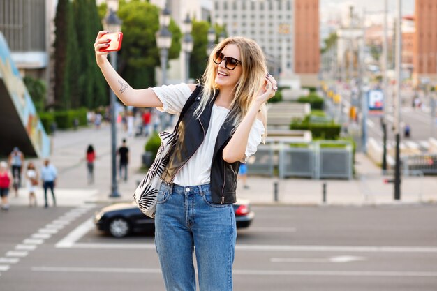 Mujer rubia bastante turista haciendo selfie en la calle