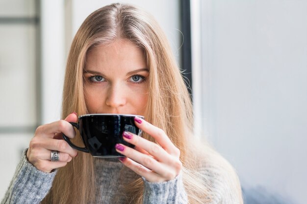 Mujer rubia bebiendo de la taza