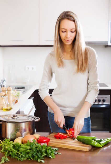 Mujer rubia casual rebanar pimiento rojo