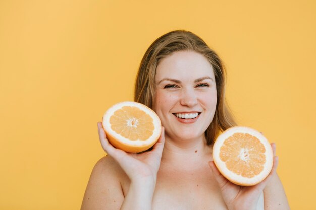 Mujer rubia con curvas sosteniendo dos naranjas frescas