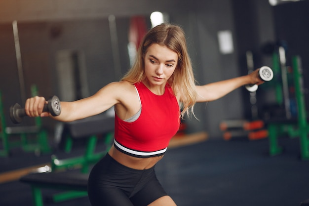 Mujer rubia deportiva en un entrenamiento de ropa deportiva en un gimnasio