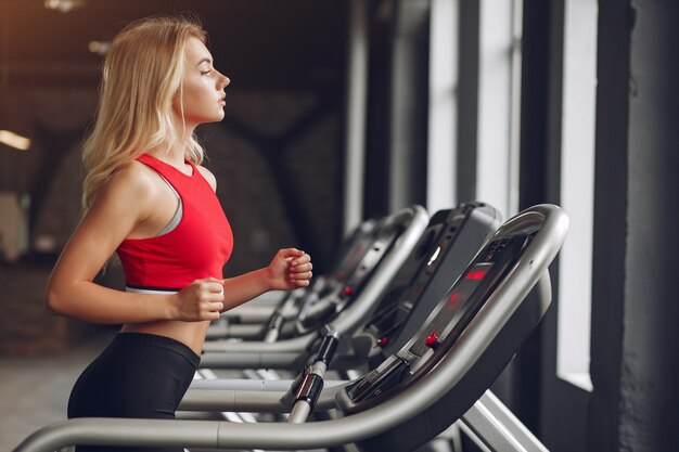 Mujer rubia deportiva en un entrenamiento de ropa deportiva en un gimnasio