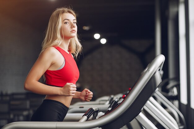 Mujer rubia deportiva en un entrenamiento de ropa deportiva en un gimnasio