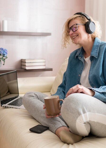 Mujer rubia escuchando música y tomando café