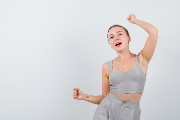 La mujer rubia está bailando sobre fondo blanco.