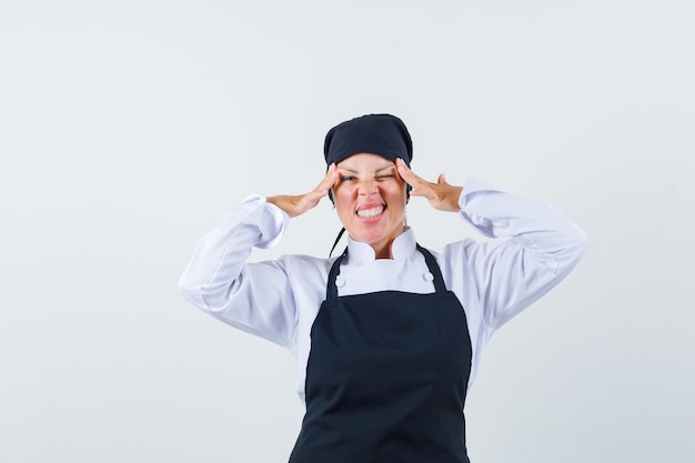 Foto gratuita mujer rubia estirando los ojos con las manos en uniforme de cocinero negro y luciendo bonita.