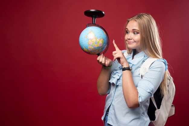 Foto gratuita mujer rubia estudiante sostiene un globo y apuntando a un lugar.