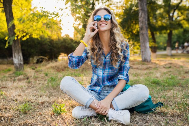 Mujer rubia feliz bastante sonriente con estilo joven en el parque en un día soleado de verano