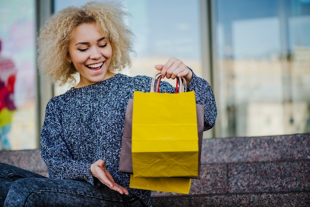 Mujer rubia feliz con bolsas de papel