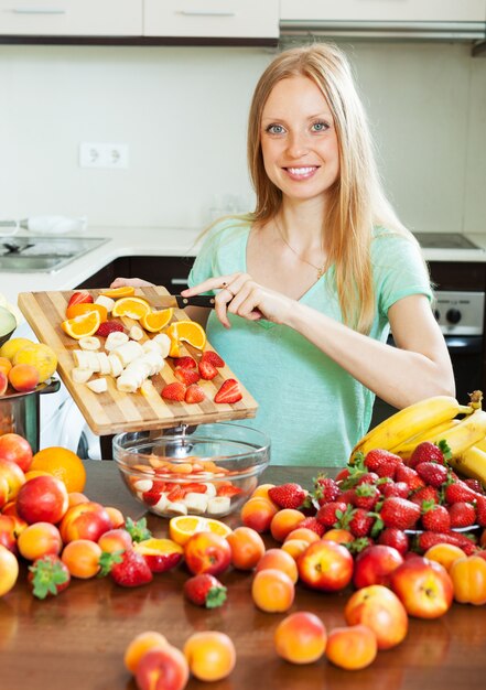 Mujer rubia feliz cortar las frutas