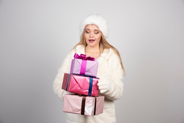 Mujer rubia feliz mirando cajas de regalo.