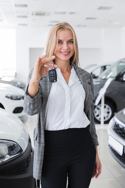 Mujer rubia feliz que sostiene la llave del coche