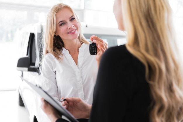 Mujer rubia feliz que sostiene las llaves del coche