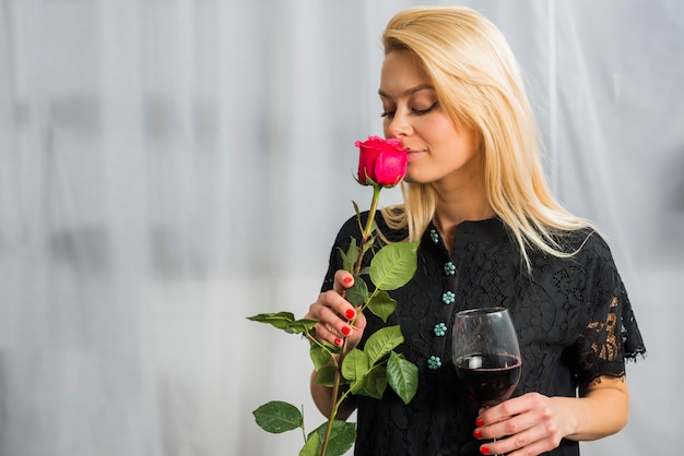 Foto gratuita mujer rubia con flor y copa de vino.